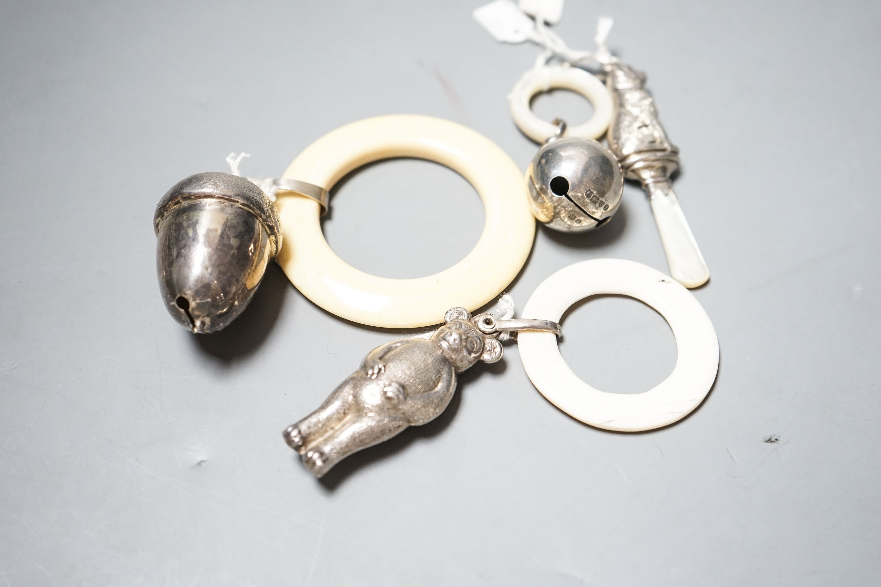 Four assorted child's silver teething rattles, including dog, bear and acorn.